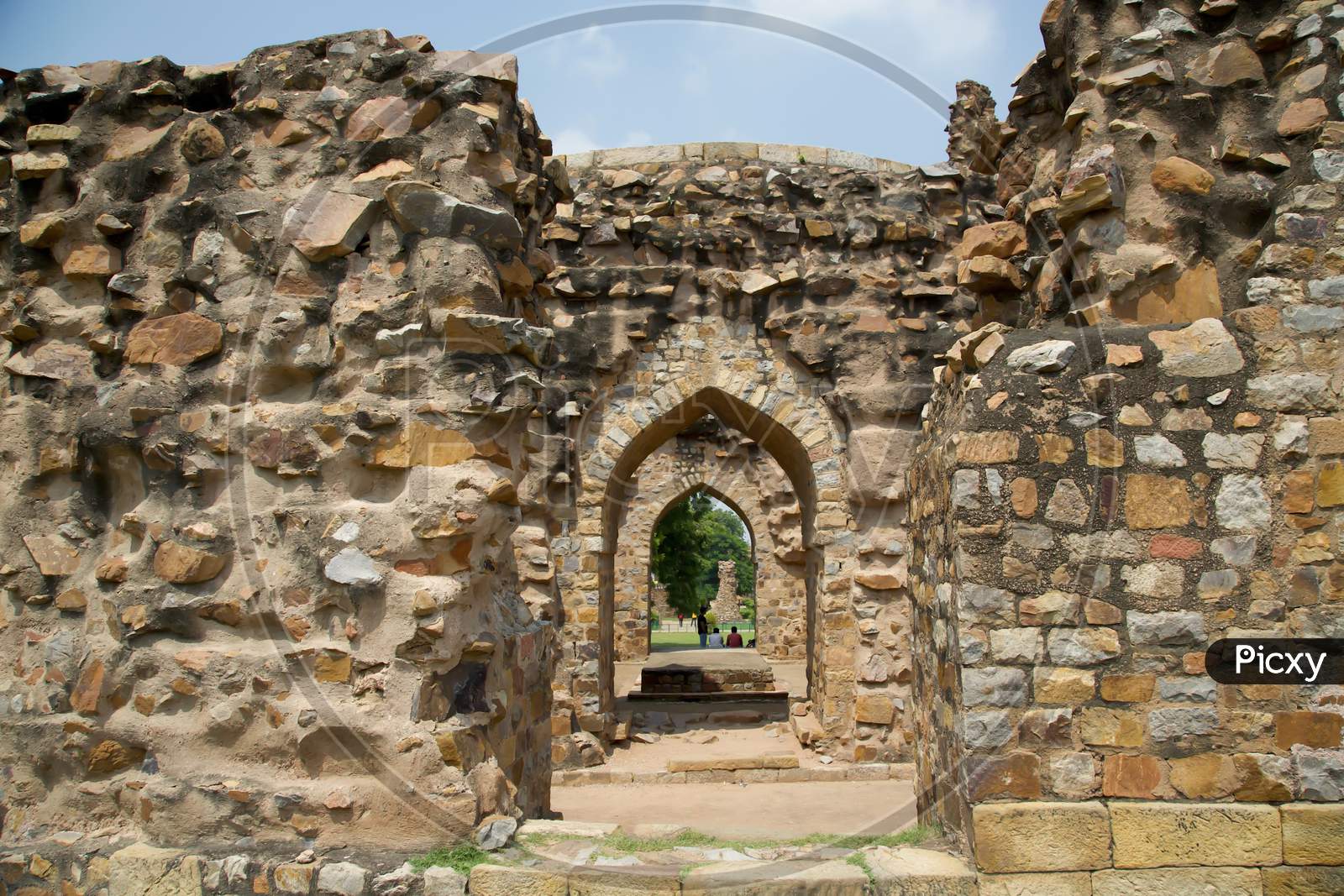 Remains Of Walls And Arches At The Qutub Complex In India. Looking Through Archways Of Ruined Buildings Made Of Stone.