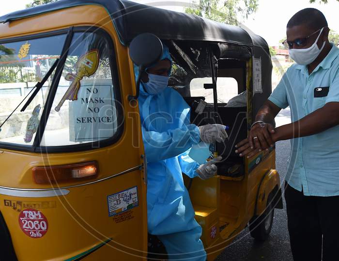An Auto Rickshaw Driver Wearing Personal Protective Equipment  (Ppe) Sprays Sanitiser On The Hands Of A Customer in Chennai, Tamil Nadu