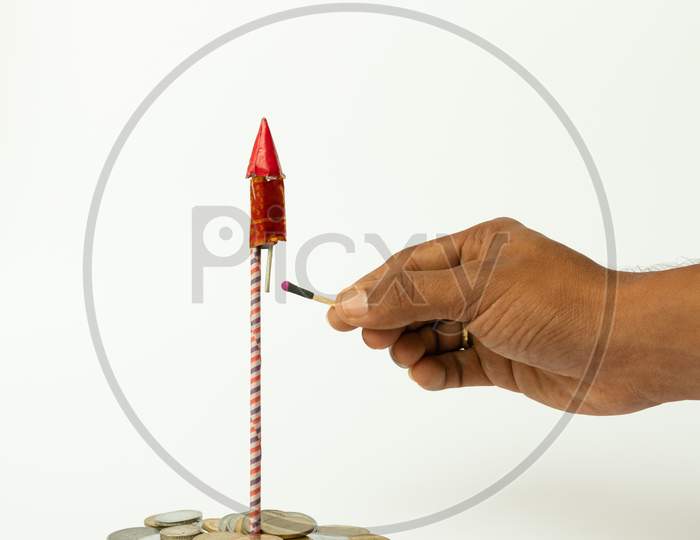 Firecracker Rocket On Stack Of Coins And Hands Buring The Rocket On Isolated Background With Copy Space