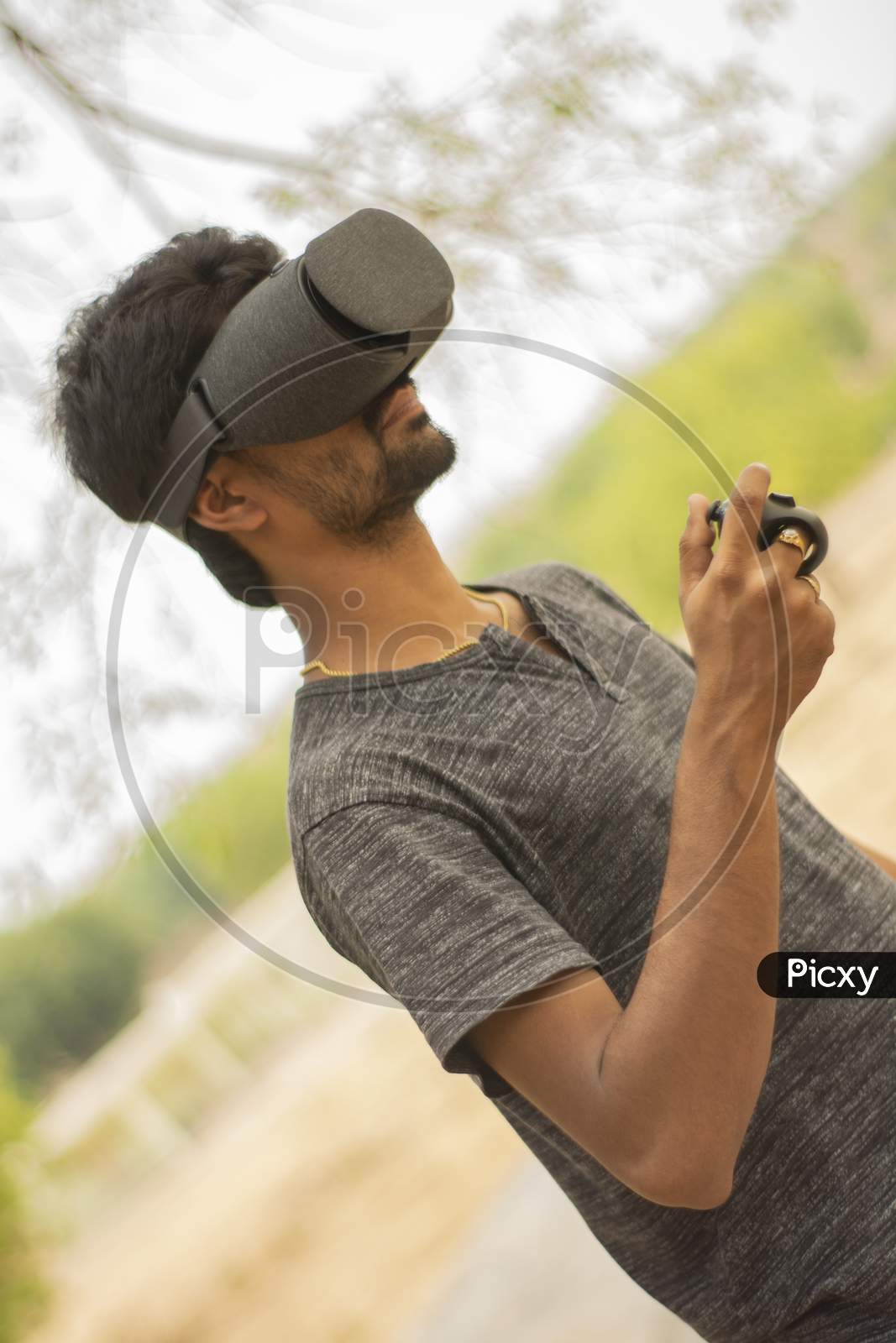 Young Man Playing Game Using A Vr Headset Glasses With Remote Controller Outside The Home.