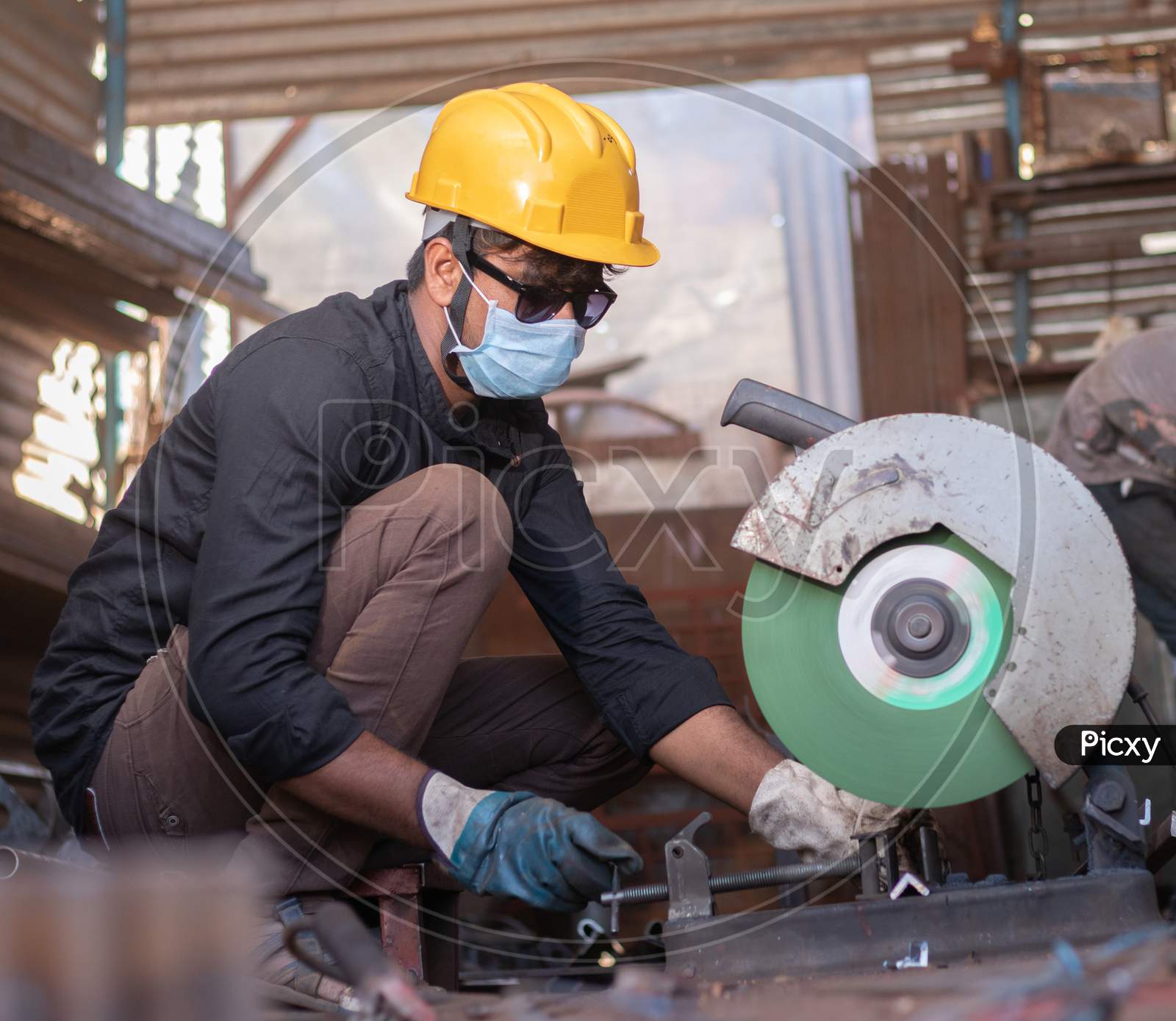 A Young Welder Cutting a Metal Piece with Goggles and Helmet