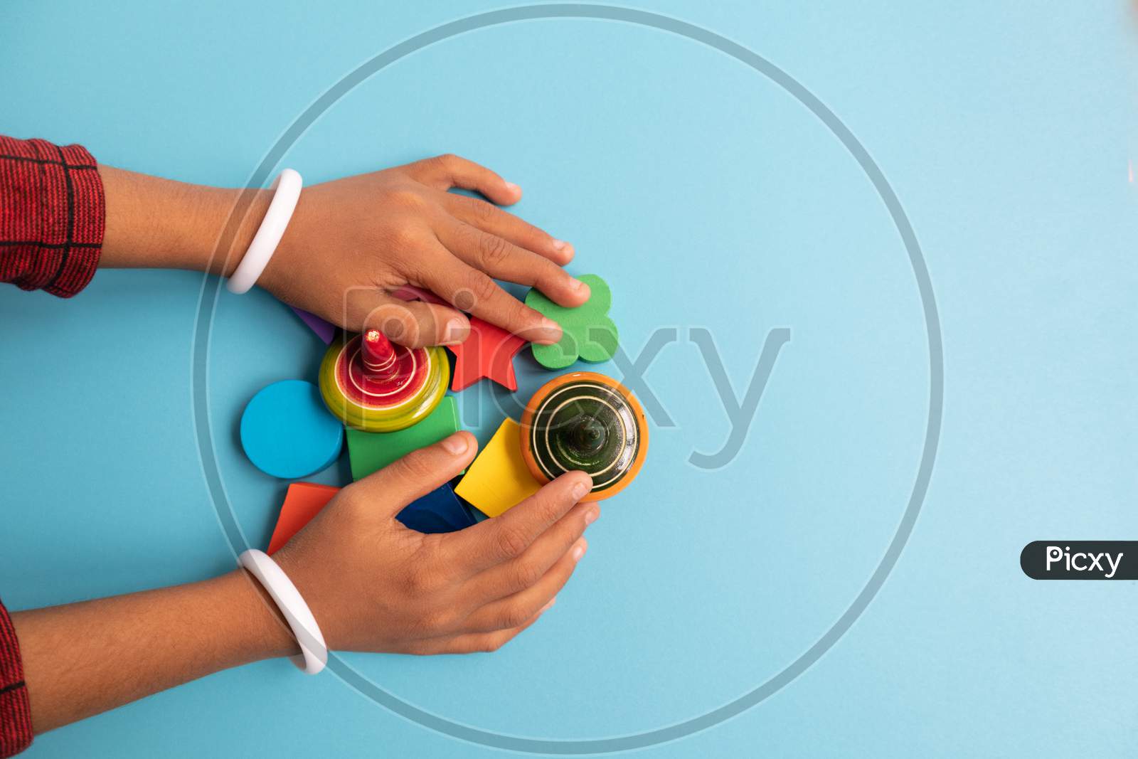 Top View Of Hand Of A Children Grabbing Colorful Wooden Building Blocks With Different Shapes For Playing Of Children On Blue Background.