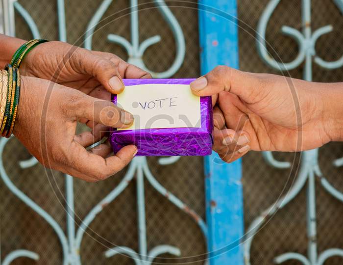 Person Giving Gift To Woman For Vote In Front Of The Door, Concept Of Showing A Gift For Vote.