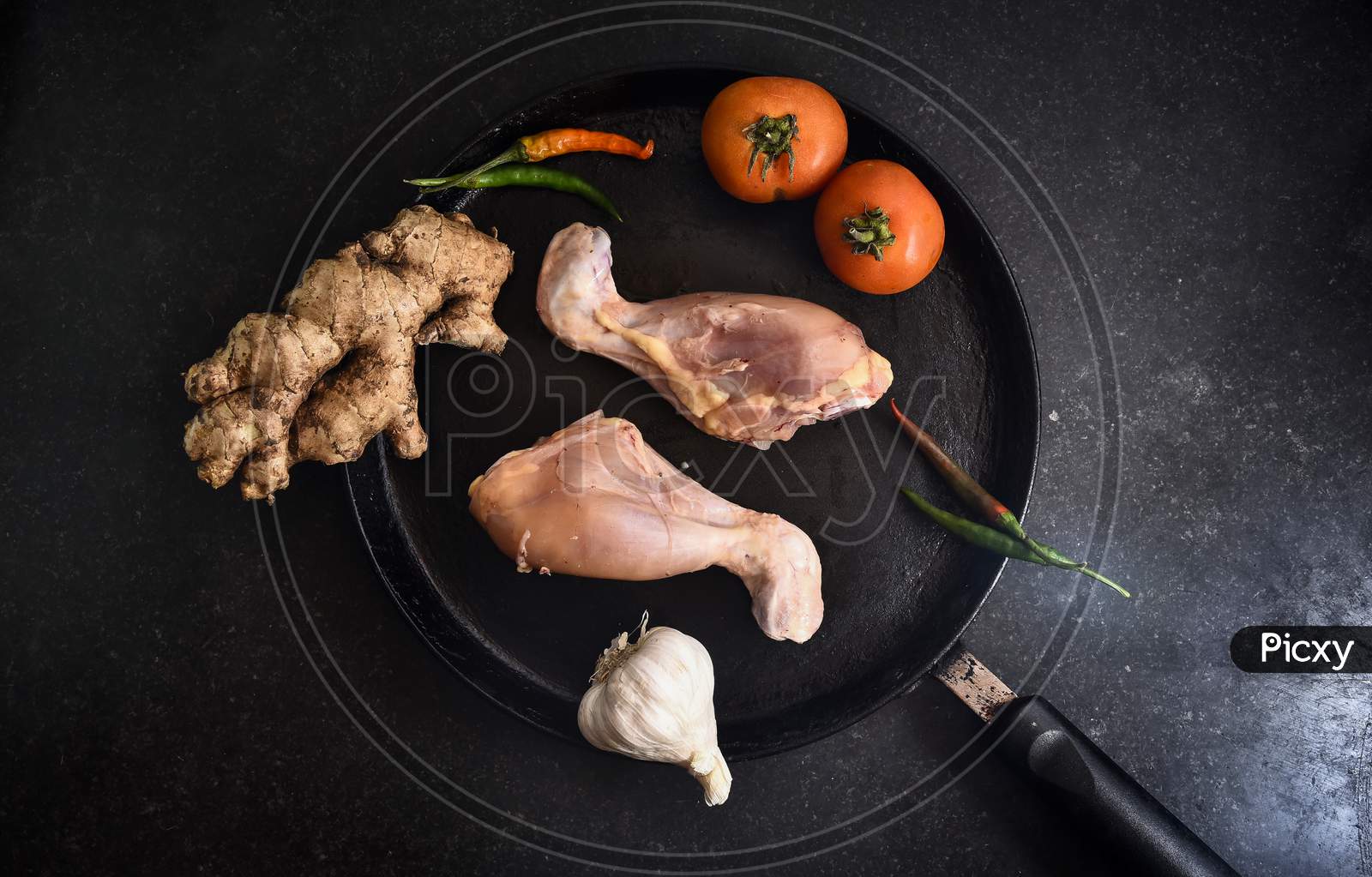 fresh Raw uncooked chicken legs, drumsticks meat on dark board, top view