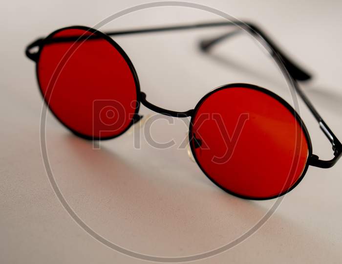 Red shaded sunglasses against a white background. A perfect gear for summer.
