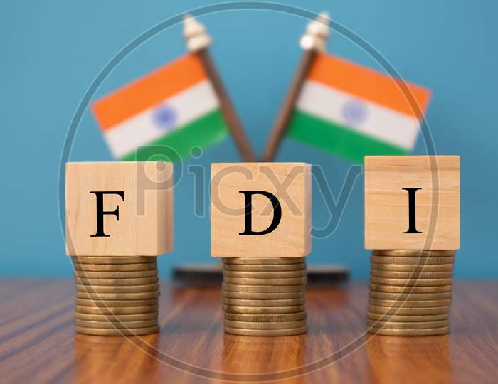 Concept Of Fdi Or Foreign Direct Investment On India In Wooden Block Letters On Stack Of Coins With Indian Flag As A Background.