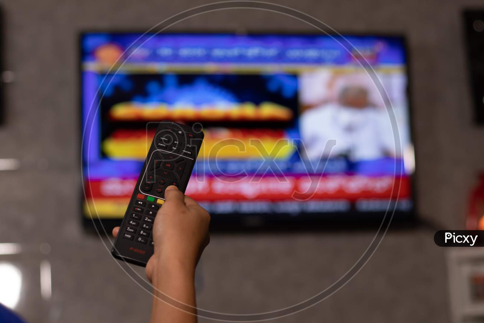Hands Holding Remote Control Watching News On Tv Screen In Out Of Focus