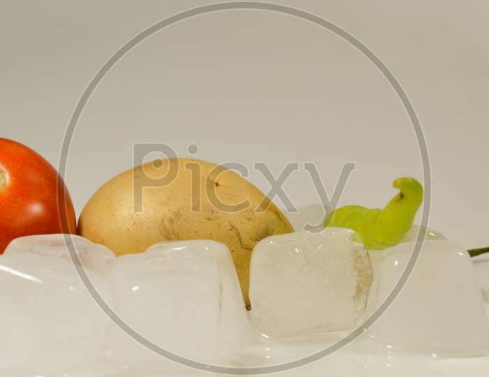 Tomato, Potato and Chillies with the ice cubes Cubes isolated with white background