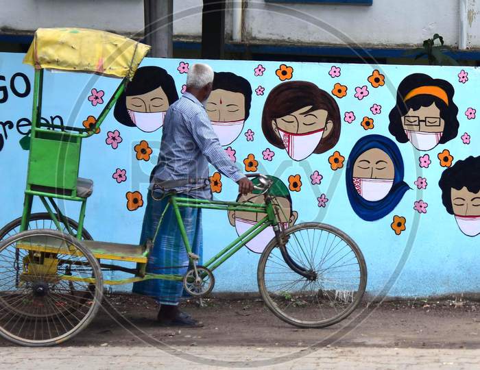 A Rickshaw Puller Looks at a Wall Graffiti of Covid-19 In Nagaon District Of Assam On June 8,2020.