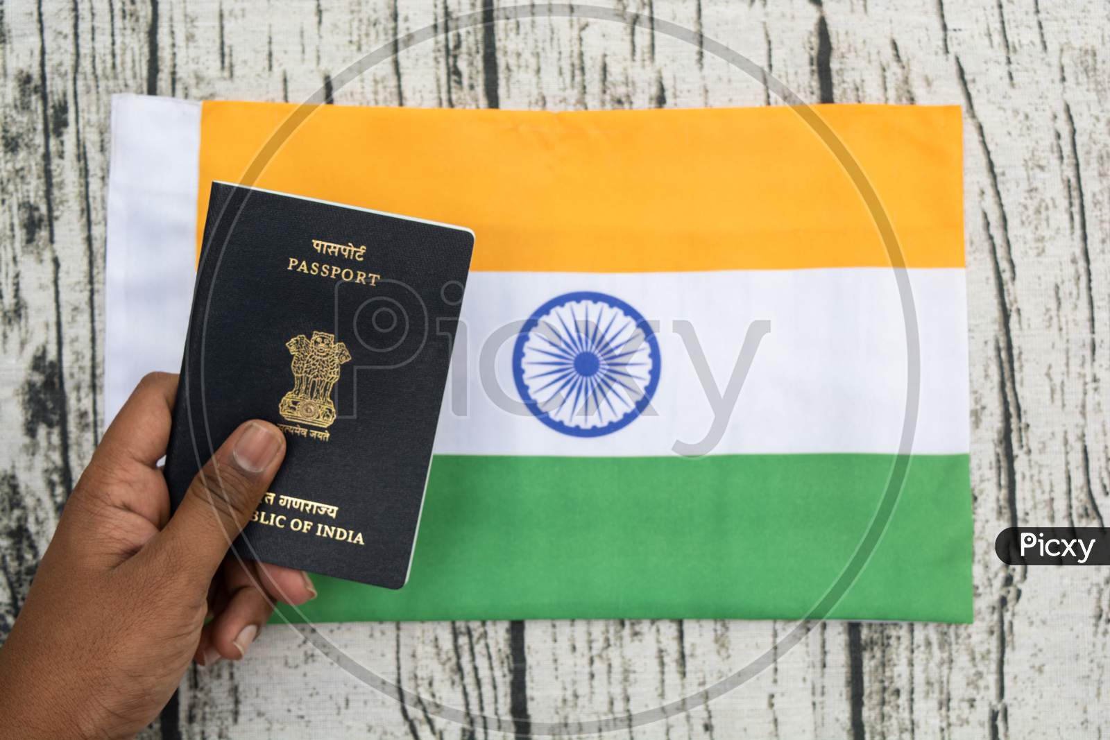 Person Holding Indian Passport With Hand On A Indian Flag As Background.