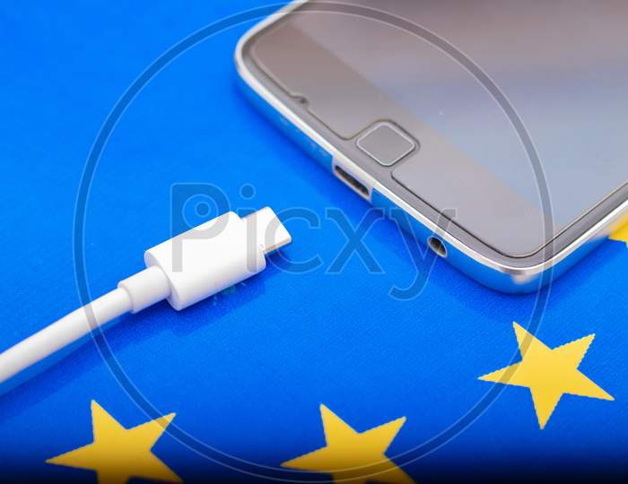 Close Up Mobile Phone Charger With Usb Type - C Cord On Eu Flag