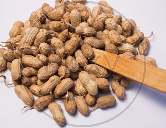 Close Up Of Peanuts Or Groundnuts With Wooden Spoon On Isolated Background
