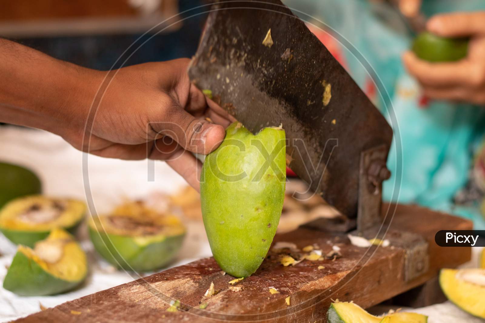 Closeuof Handing Cutting Ripe Mango For Making Picke In India With Indian Vegetable Cutter.