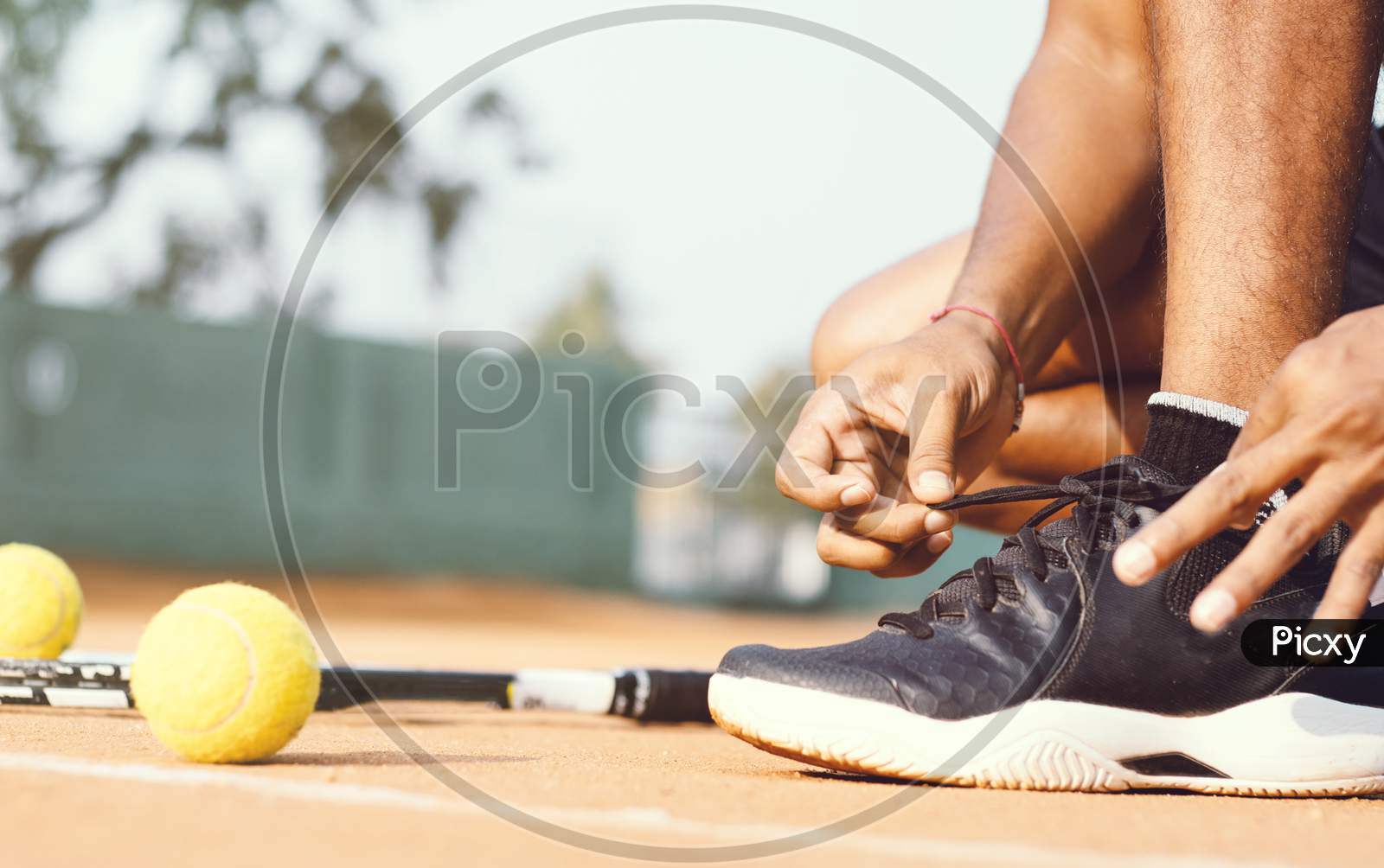 Close up shot of a Young Indian Man tying Shoelace in a Tennis Court