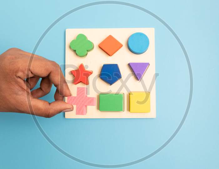 Top View Hands Picking Up One Colorful Wooden Building Blocks In Different Shapes On Blue Background.