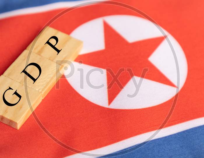 Gross Domestic Product Or Gdp Of North Korea In Wooden Block Letters On North Korean Flag.