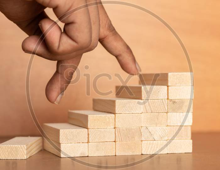 Hand Liken Business Person Jumping Directly From Bottom To Top Of The Wooden Toy Staircase On Wooden Textured Background