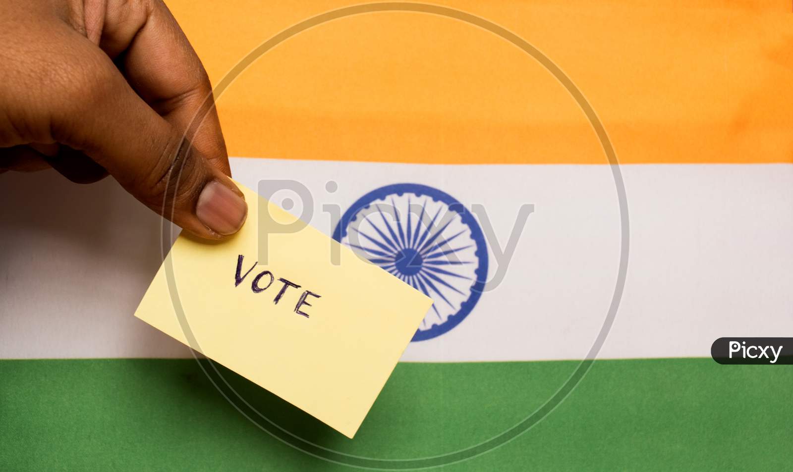 Voting Concept - Person Holding Hand Written Voting Sticker On India Flag.