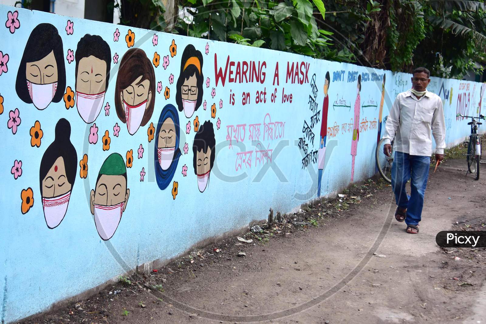A Man Walks In Front Of a Wall Graffiti of COVID-19 In Nagaon District Of Assam On June 8,2020.