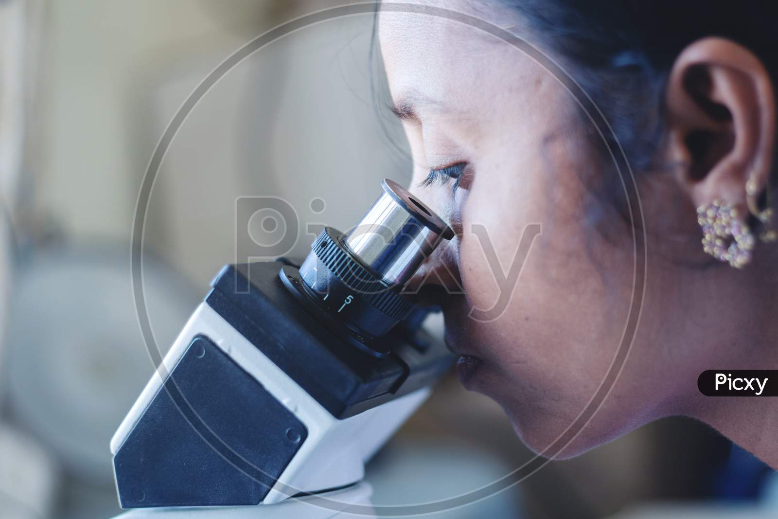 Close Up Of Woman Using A Microscope In A Laboratory - Female Scientist Busy In Looking Into Microscope.