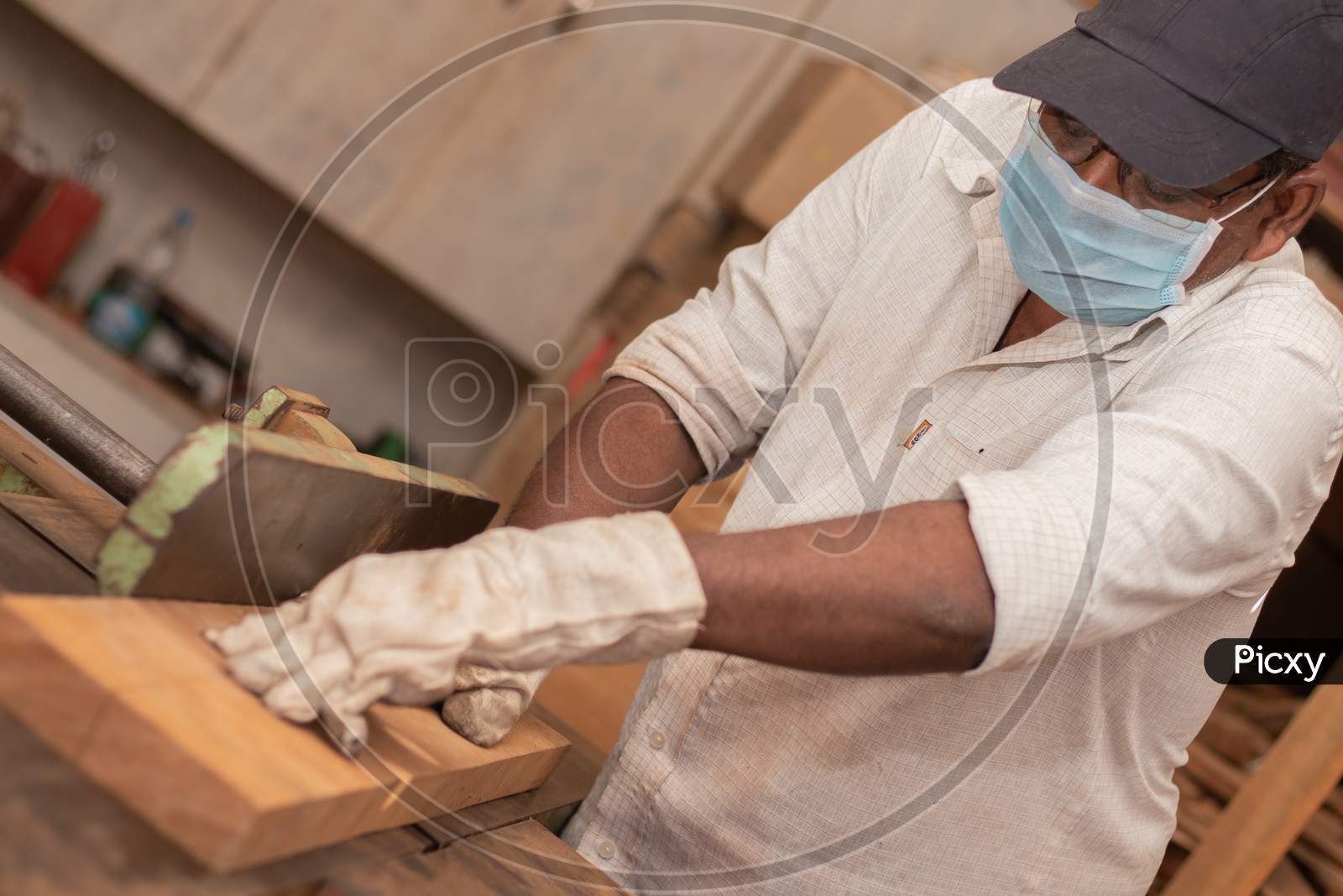 A Carpenter cutting Large Wooden Board with A Mask due to Pandemic or Corona Virus Effect