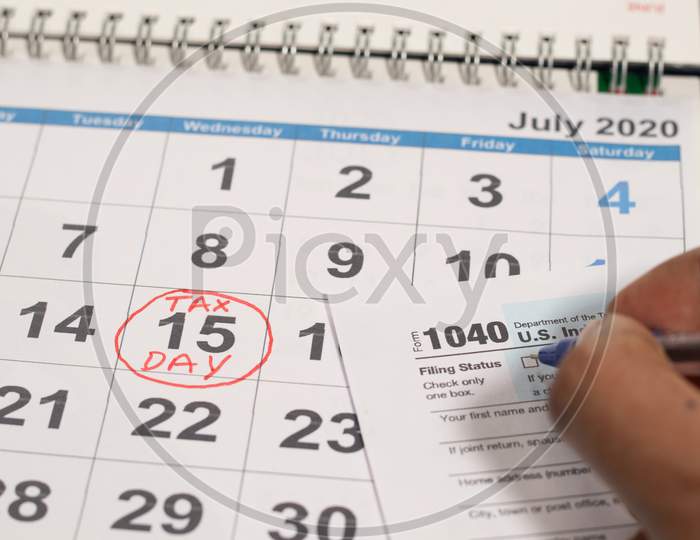 Concept Of Filling Tax Form Before Deadline July 15Th With July 15Th Marked As Tax Day On Calendar As Background.