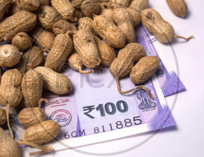 Close Up Of Peanuts Or Groundnuts With Indian Currency Below On Isolated Background