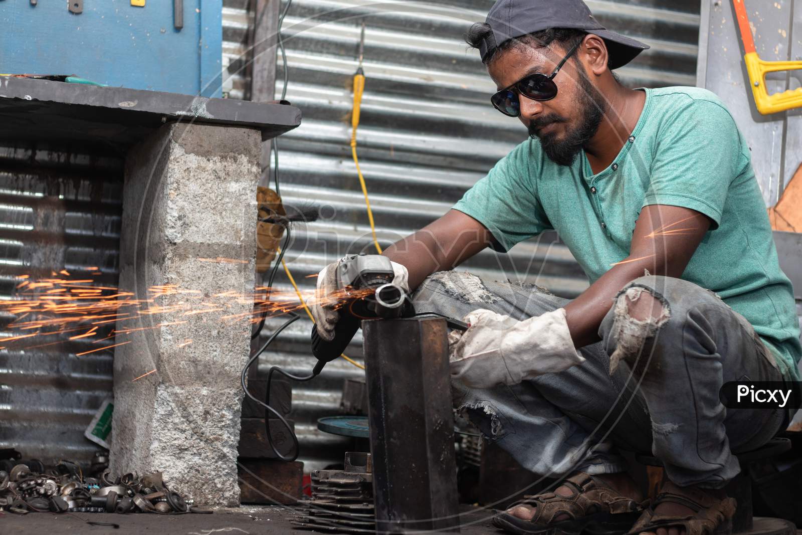 A Young Welder Cutting a Metal Piece with Goggles