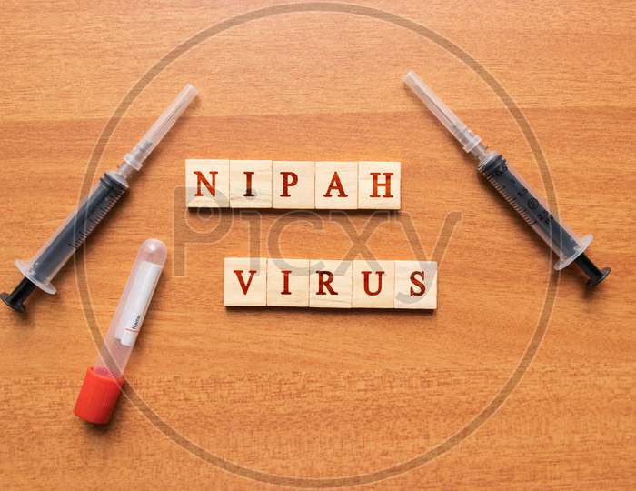 Nipah Virus On Wooden Textured Background With Syringe And Vacutainer Blood Collection Tube