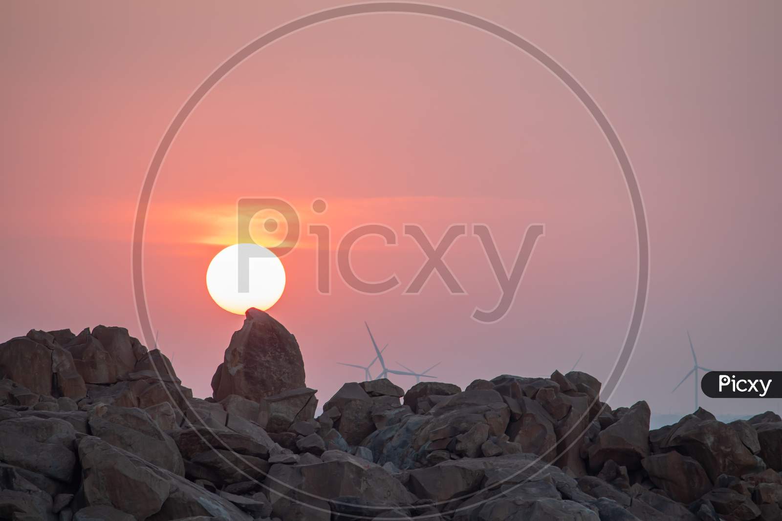 Huge Sun during Sunset with Rocks in the Foreground