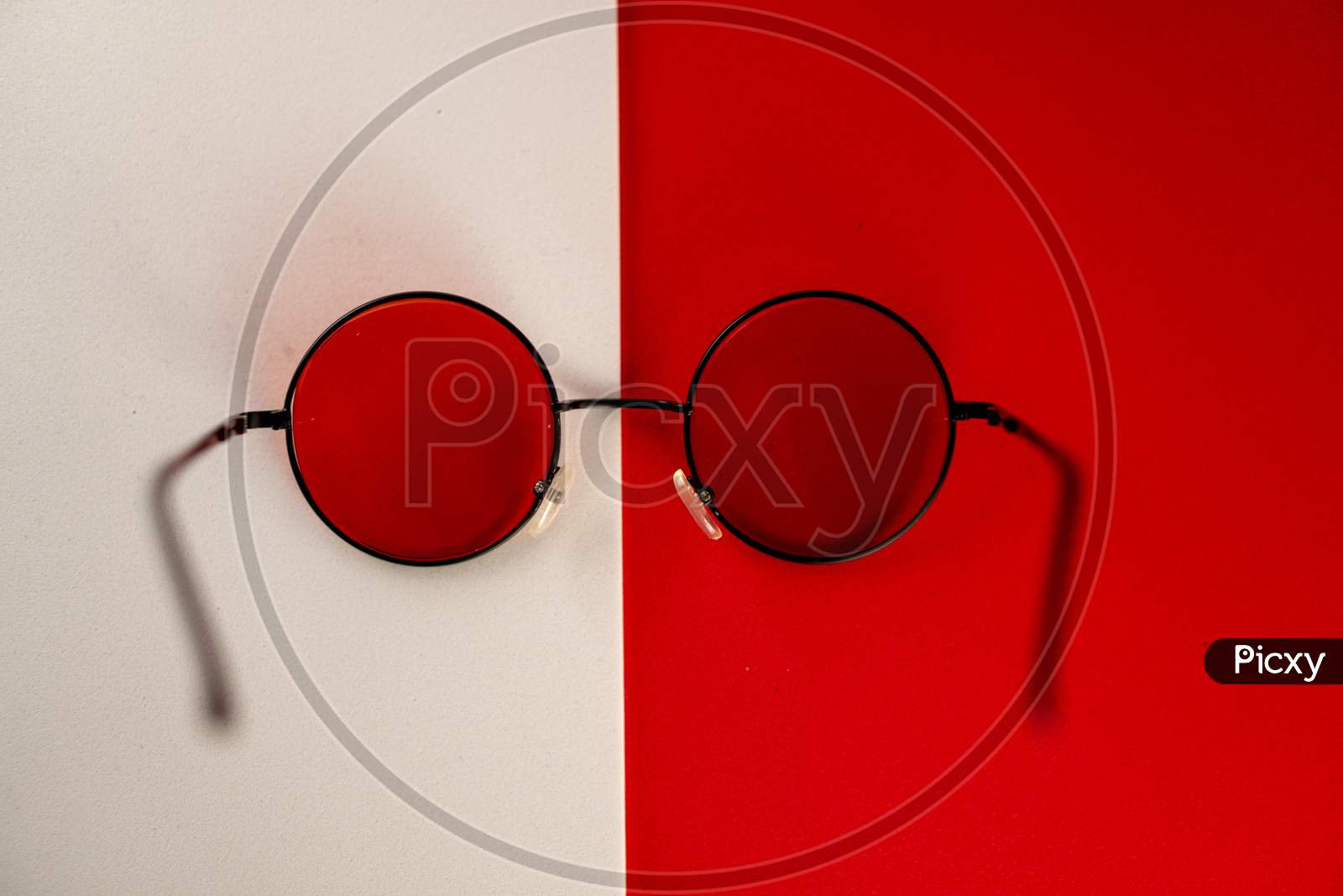 Red shaded sunglasses against a matching red and white background. A perfect gear for summer.