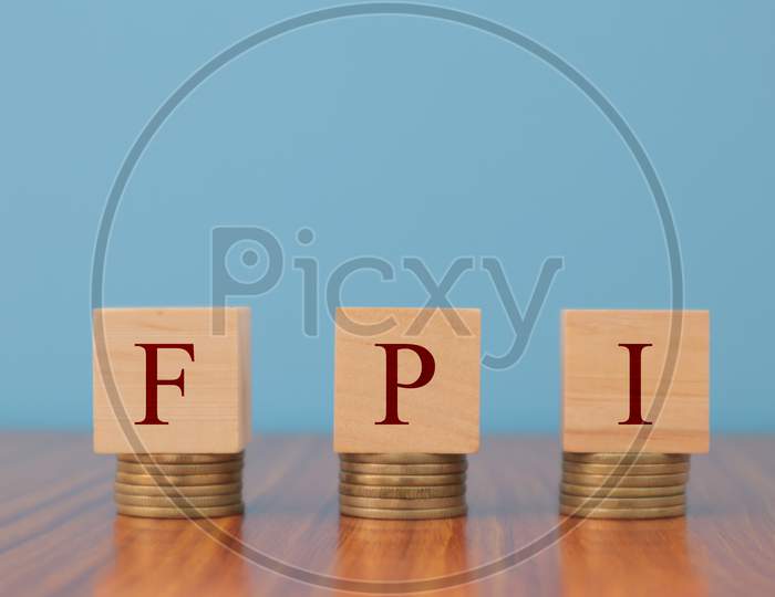 Concept Of Fpi Or Foreign Portfolio Investment In Wooden Block Letters On Stack Of Coins.