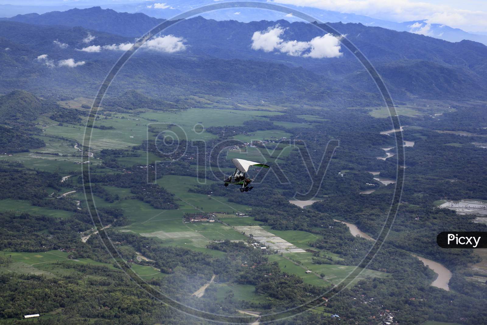 The Microlight trike passes over the green and the iconic river, Progo River