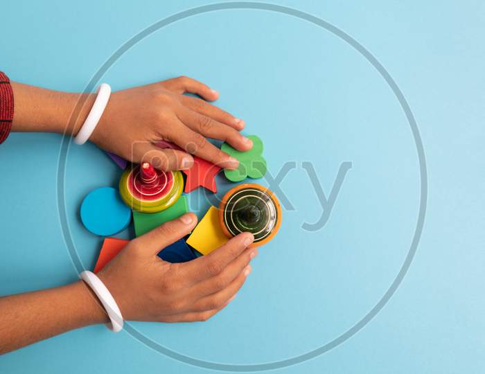 Top View Of Hand Of A Children Grabbing Colorful Wooden Building Blocks With Different Shapes For Playing Of Children On Blue Background.