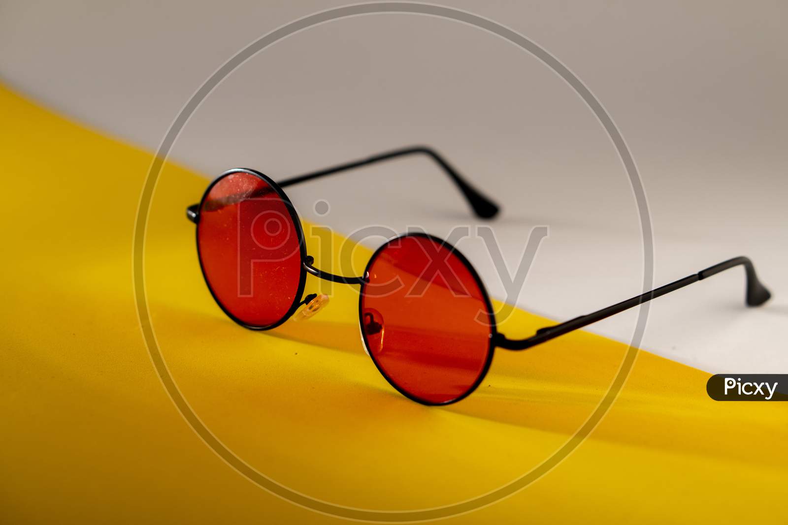 Red shaded sunglasses against a matching yellow and white background. A perfect gear for summer.