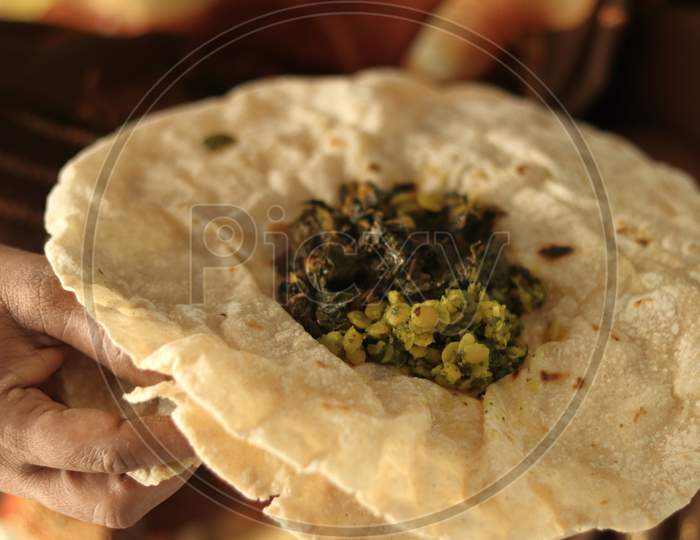Closeup Of Woman Eating South Indian North Karnataka Peoples Daily Healhy Breakfast Jowar Roti Or Rotti Or Bhakri With Dal Curry In Hand Without Using Plate.