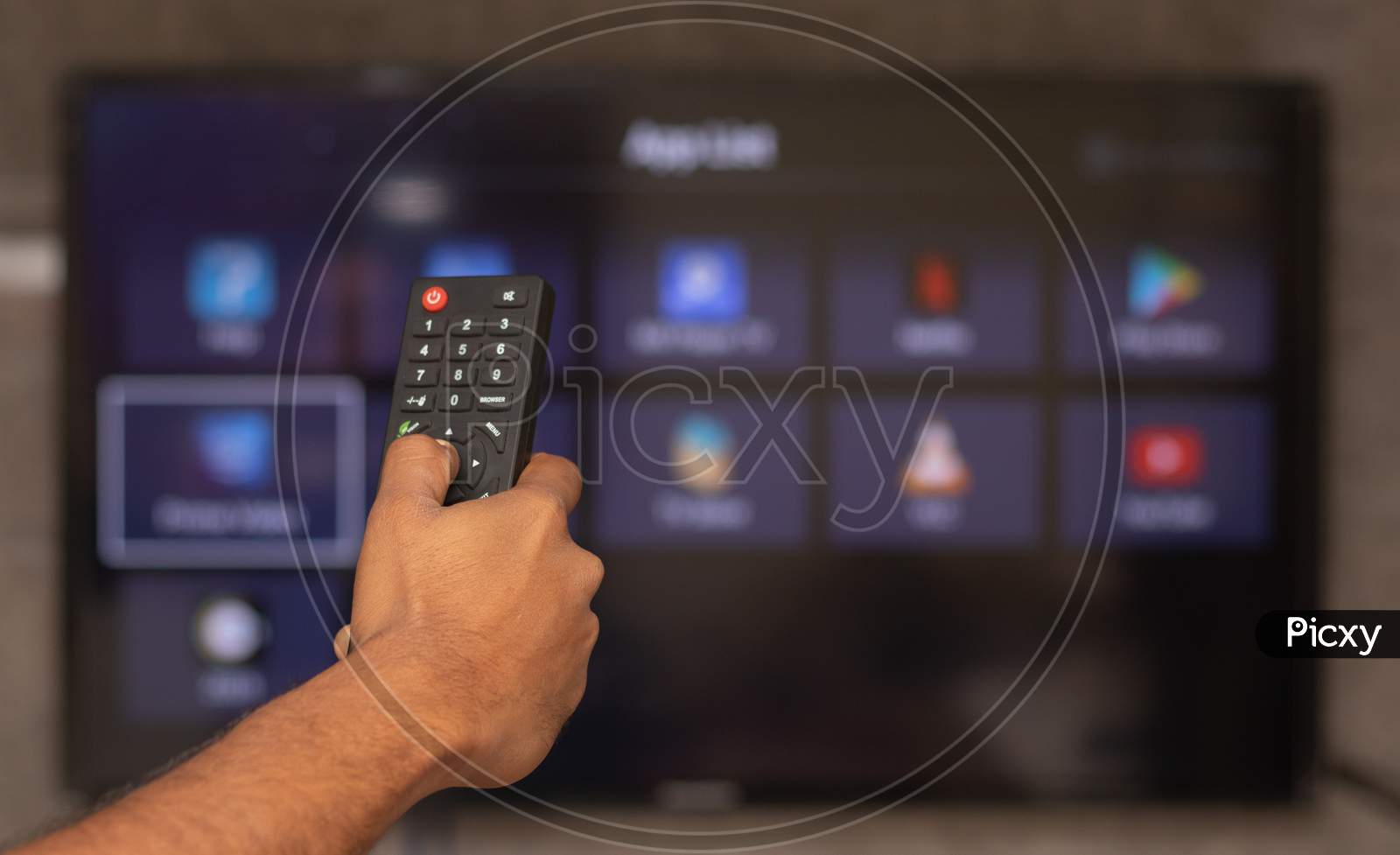 Hands Holding Remote Control With Different Online Subscription Apps On Tv Screen In Out Of Focus