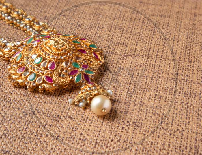 Gold Guttapusalu Necklace With Gemstones A Traditional Indian Wedding Jewelry On Wooden Textured Background.