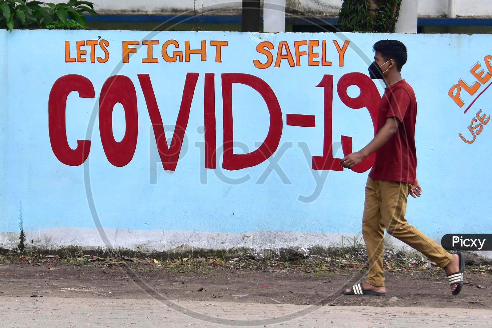 A Man Walks In Front Of a Wall Graffiti of COVID-19 In Nagaon District Of Assam On June 8,2020.