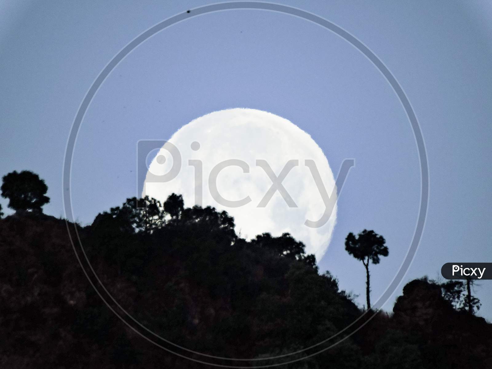 super moon rising behind the hills