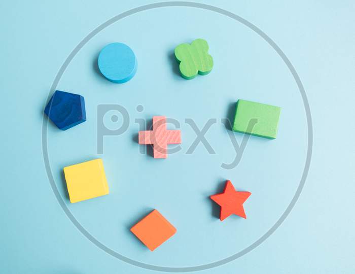 Top View Colorful Wooden Building Blocks With Different Shapes For Developing And Entertainment Of Children On Blue Background.
