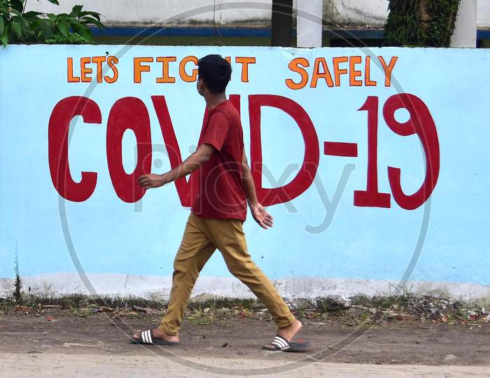 A Man Walks In Front Of Wall Graffiti  of COVID-19 In Nagaon District Of Assam On June 8,2020.