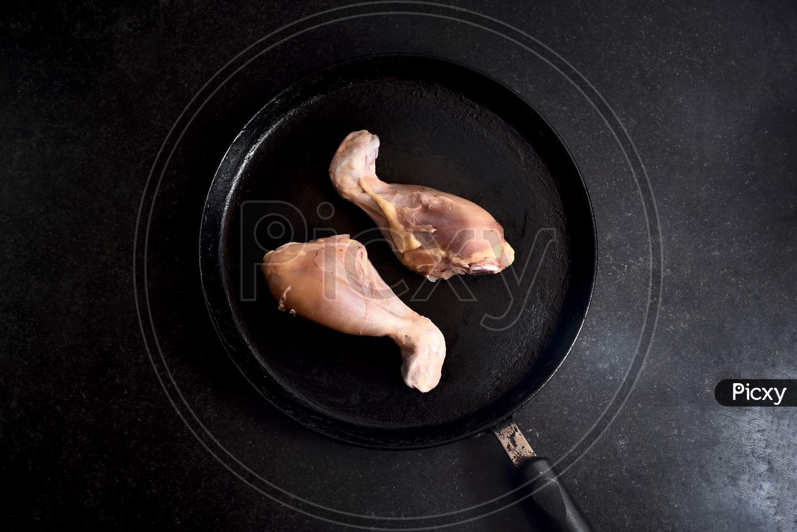 fresh Raw uncooked chicken legs, drumsticks meat on dark board, top view
