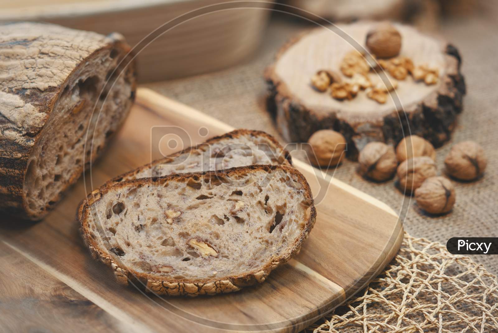 Two slices of walnut bread with other walnuts next to it.