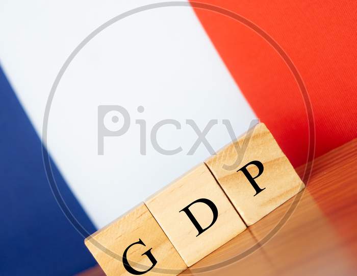 Gross Domestic Product Or Gdp Of France In Wooden Block Letters On Table, France Flag As A Background.