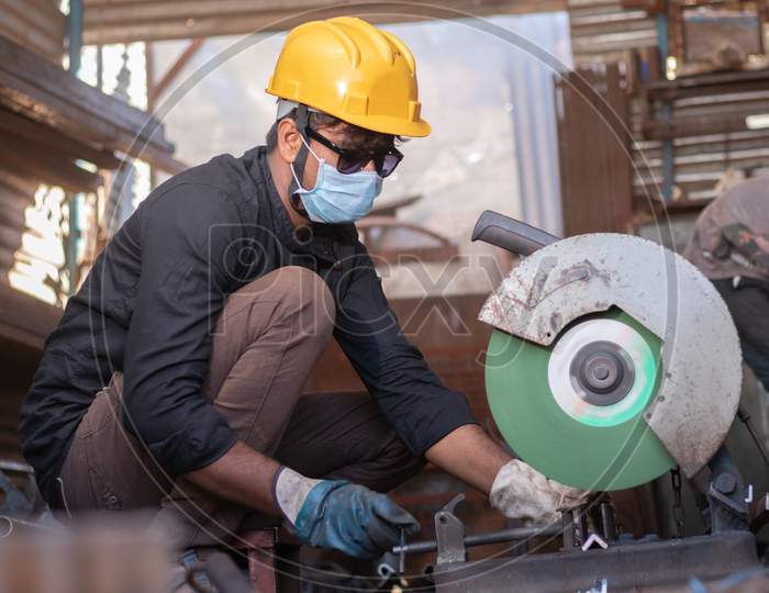 A Young Welder Cutting a Metal Piece with Goggles and Helmet