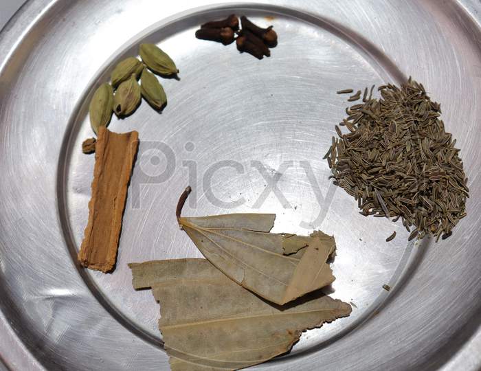Various herbs and powder spices steel plate on black background top view