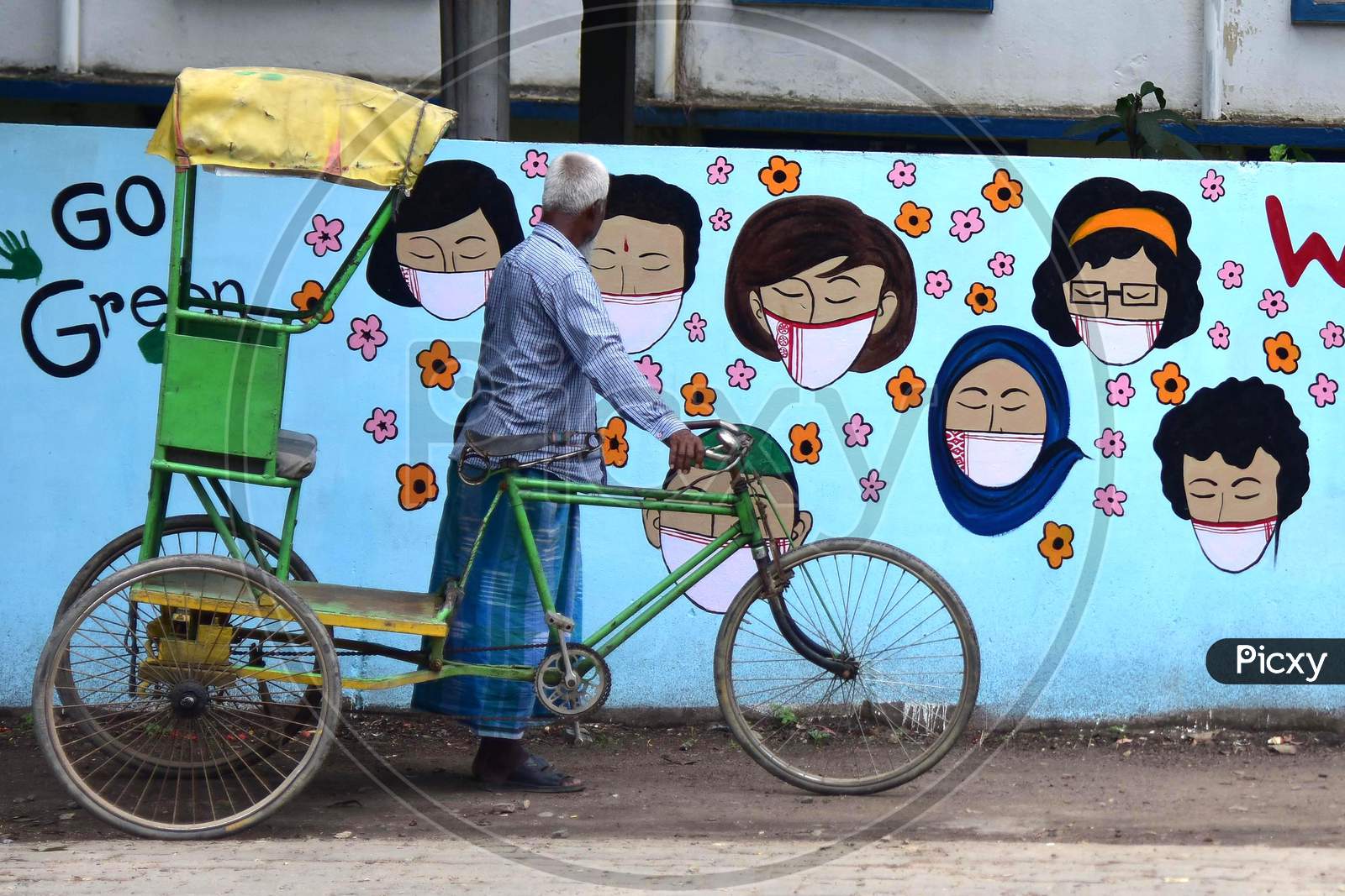 A Rickshaw Puller Looks at a Wall Graffiti of Covid-19 In Nagaon District Of Assam On June 8,2020.