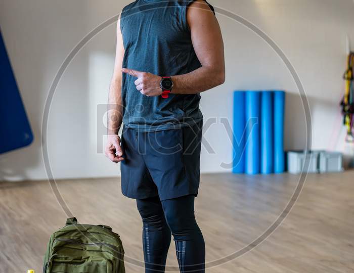 Portrait Of motivated Lebanese Boot Camp Instructor In Gym Hall. Rope, Dumbbells And Sandbag On Wooden Floor.