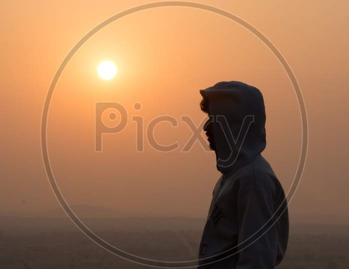 Silhouette Of A Young Man With Sun In Background